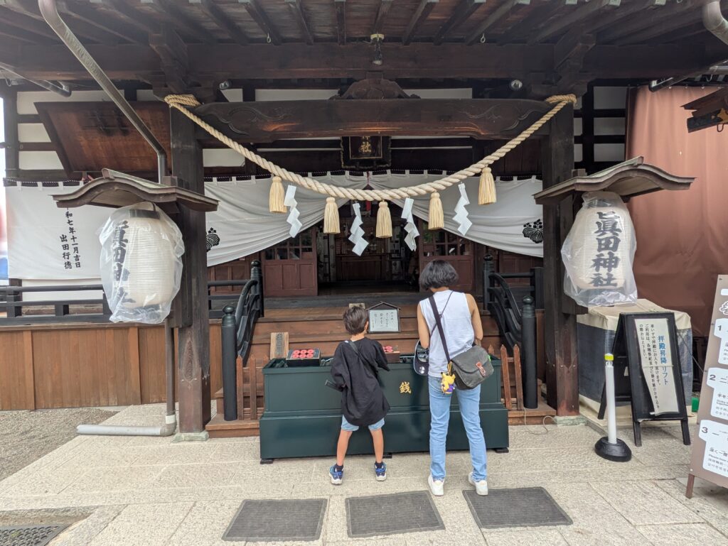 父母与孩子在真田神社拜殿前参拜祈福的情景