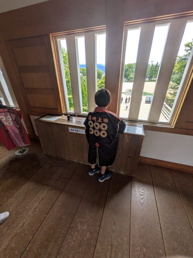 身穿信州上田法被的孩子在真田神社橹内眺望上田城迹公园