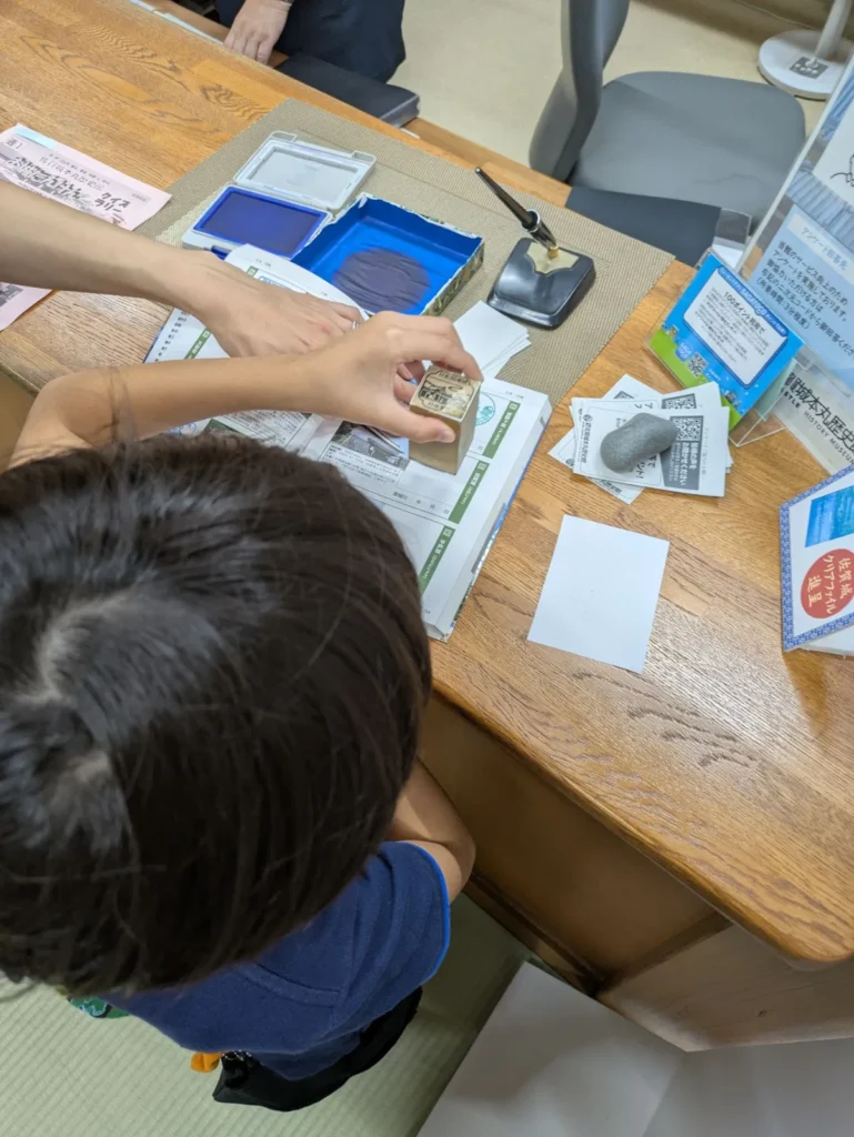 A child stamping the 100 Fine Castles of Japan stamp at the Saga Castle History Museum reception